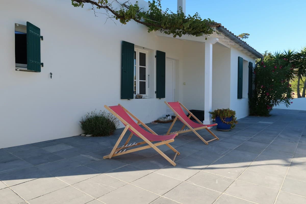 Two red canvas patio chairs beside a white house